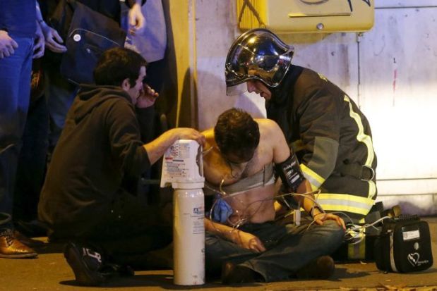 Firefighters assist an injured man near the Bataclan Concert Hall. Source: Reuters/ Christian Hartmann